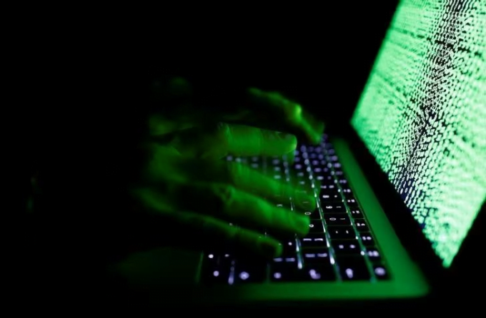 A man types on a computer keyboard with a screen displaying lines of code. Photo: Reuters