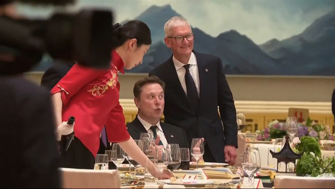 Musk's expression while posing for a photo with Apple CEO Tim Cook in a video that went viral on social media. (Screenshot)
